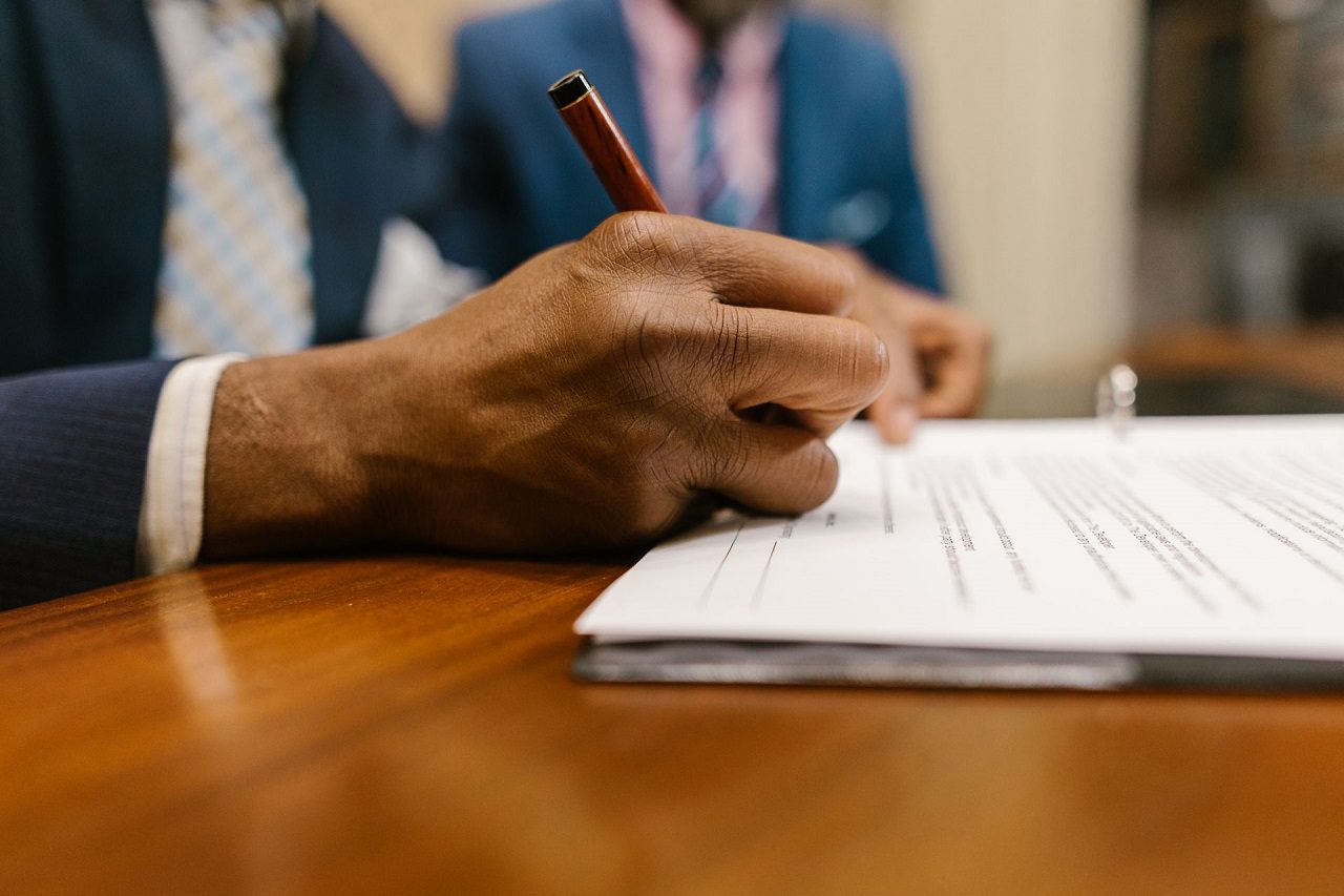 close-up-shot-of-a-person-writing-on-a-contract